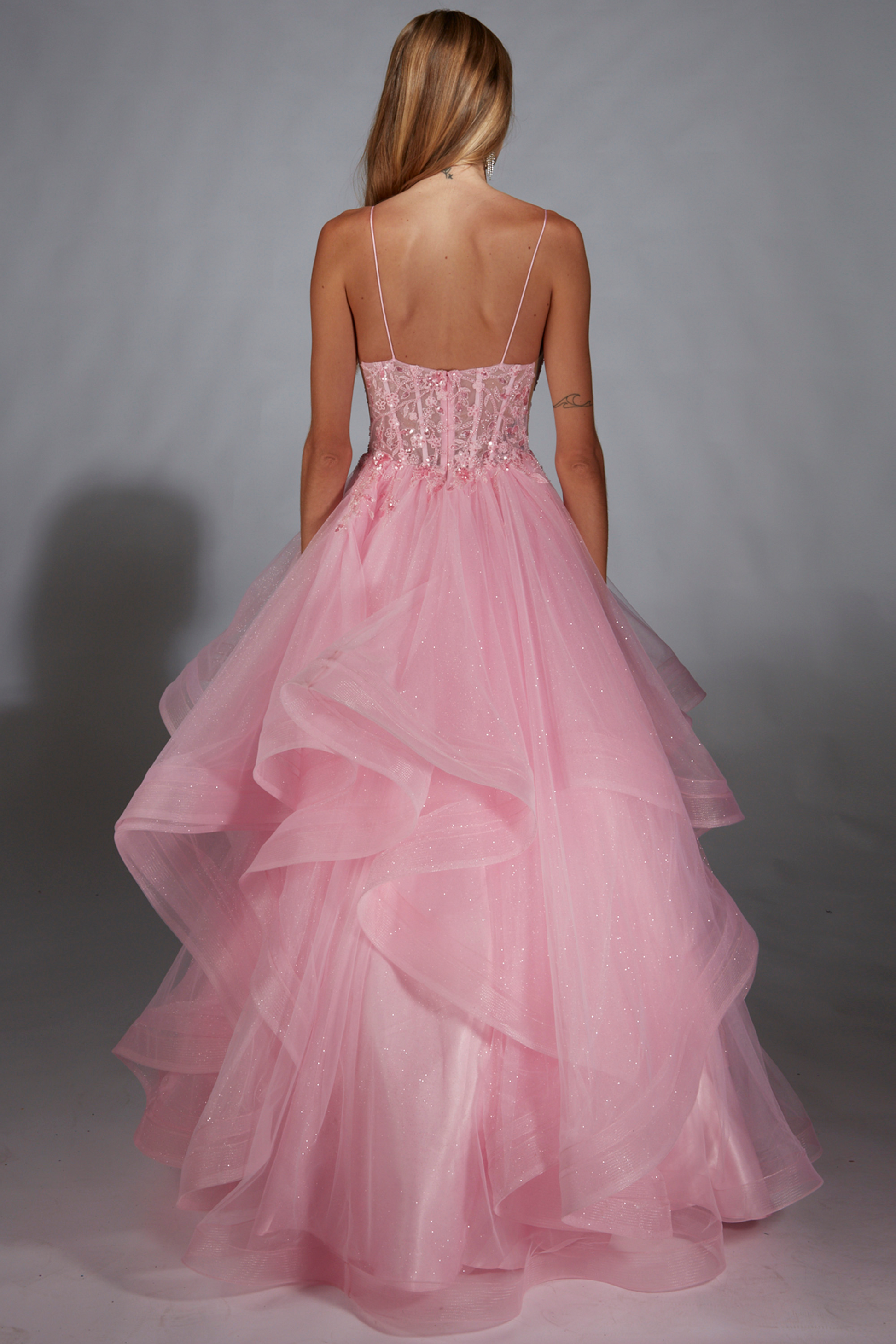 Pink formal dress with a sheer bodice on a plain background
