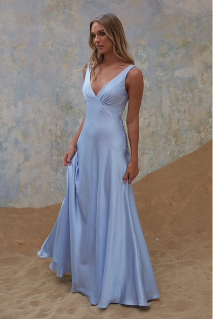 Woman in a light blue bridesmaid dress, formal dress standing against a textured wall and sand background