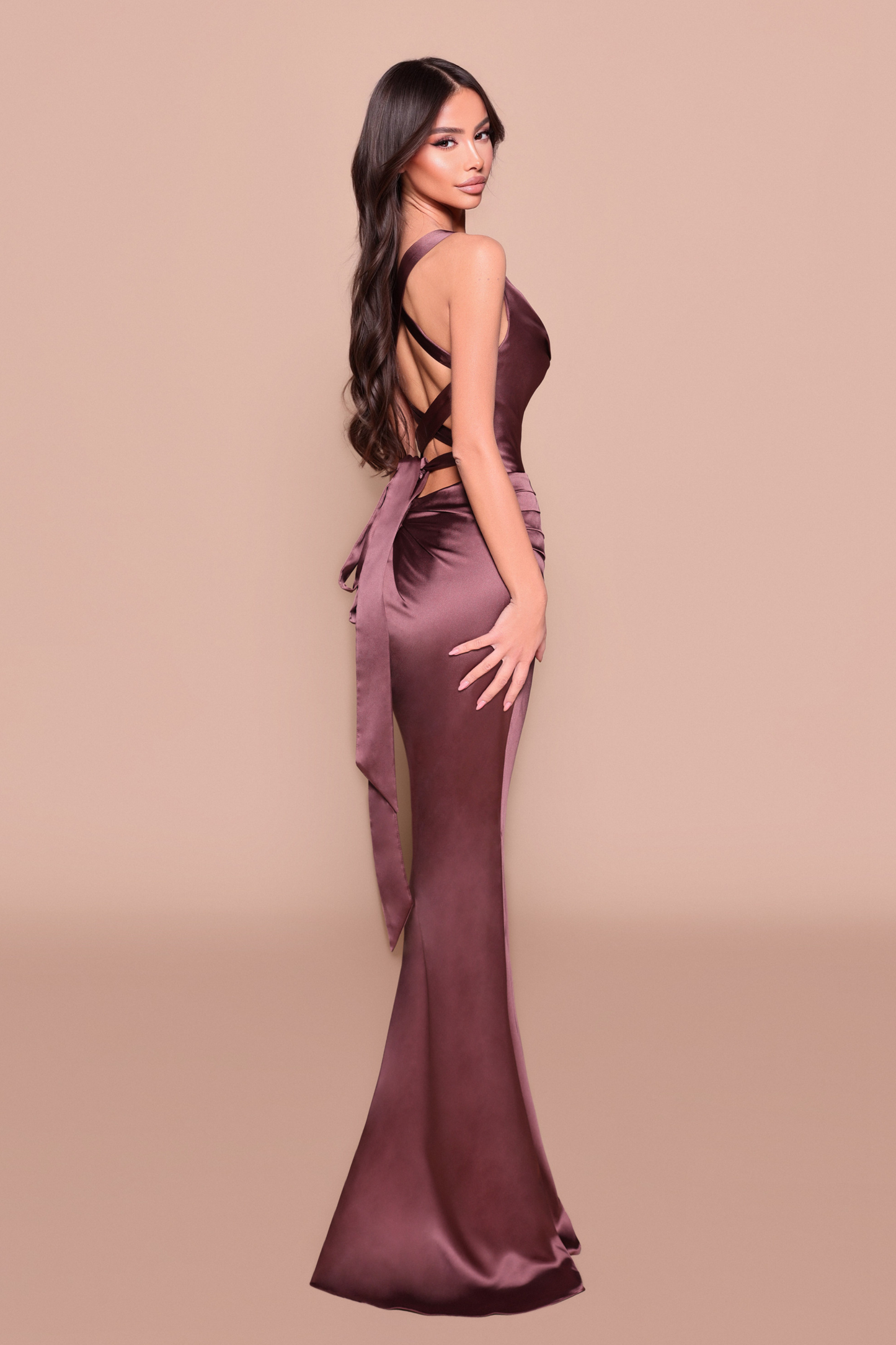 Woman wearing a long fitted, elegant chocolate dress showing back design