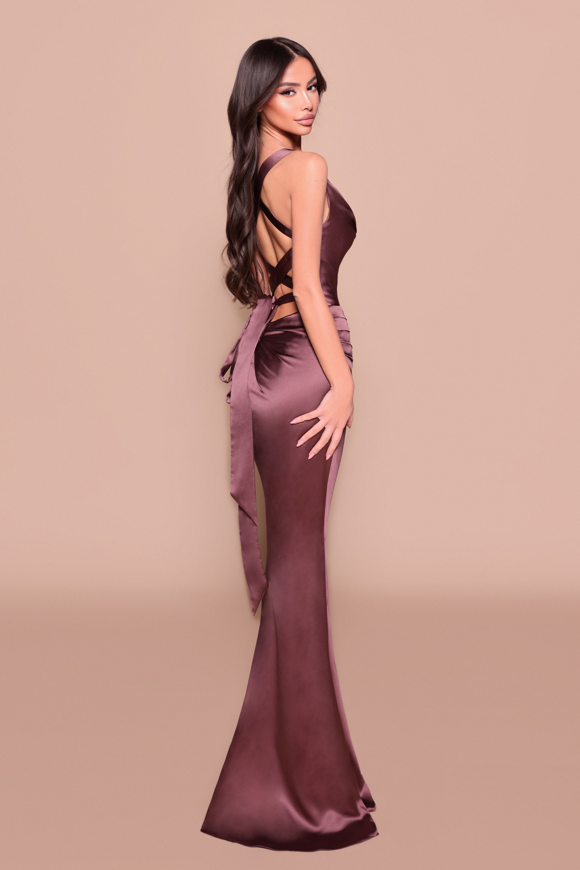 Woman wearing a long fitted, elegant chocolate dress showing back design