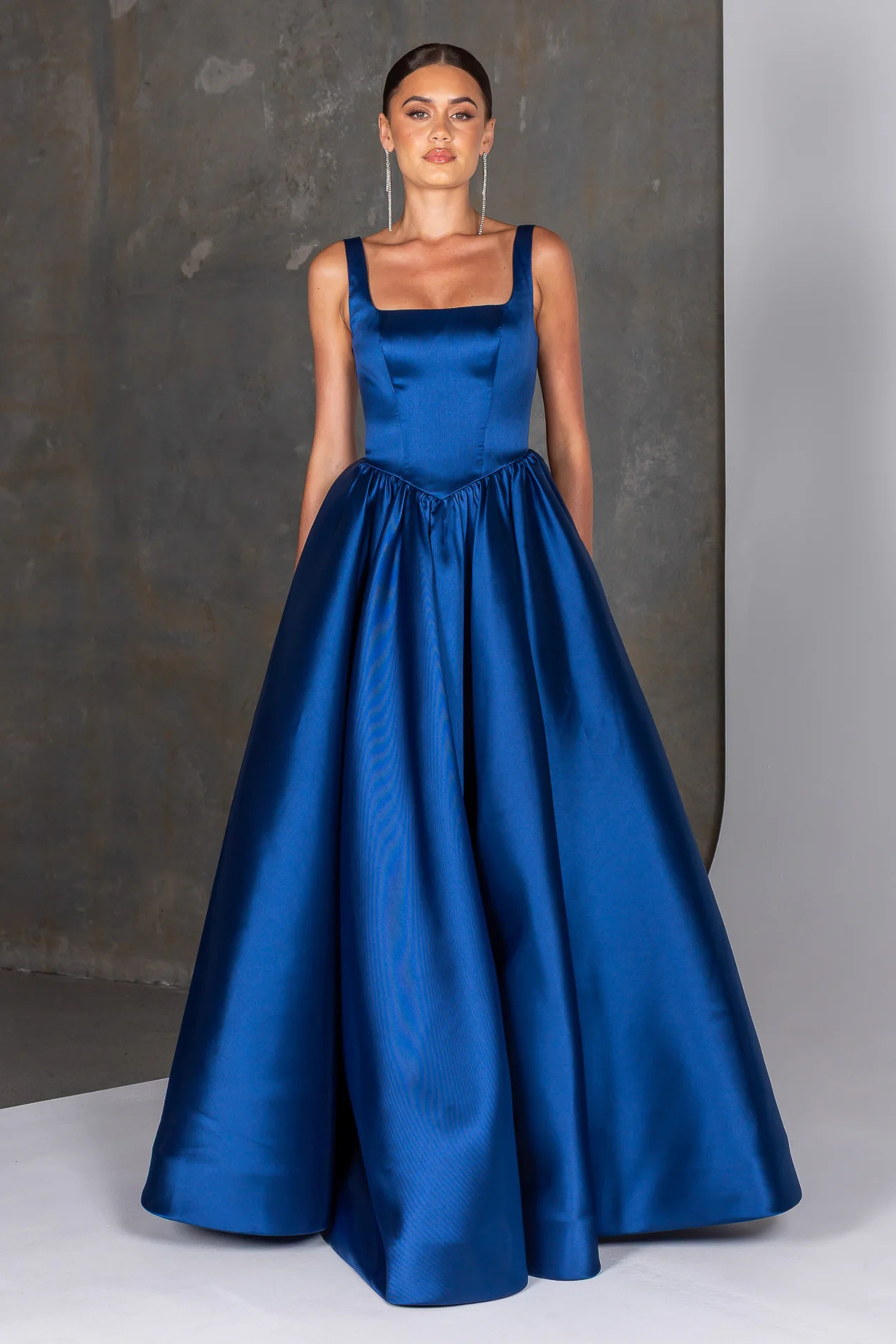 Woman wearing a navy Mikado gown against a neutral background