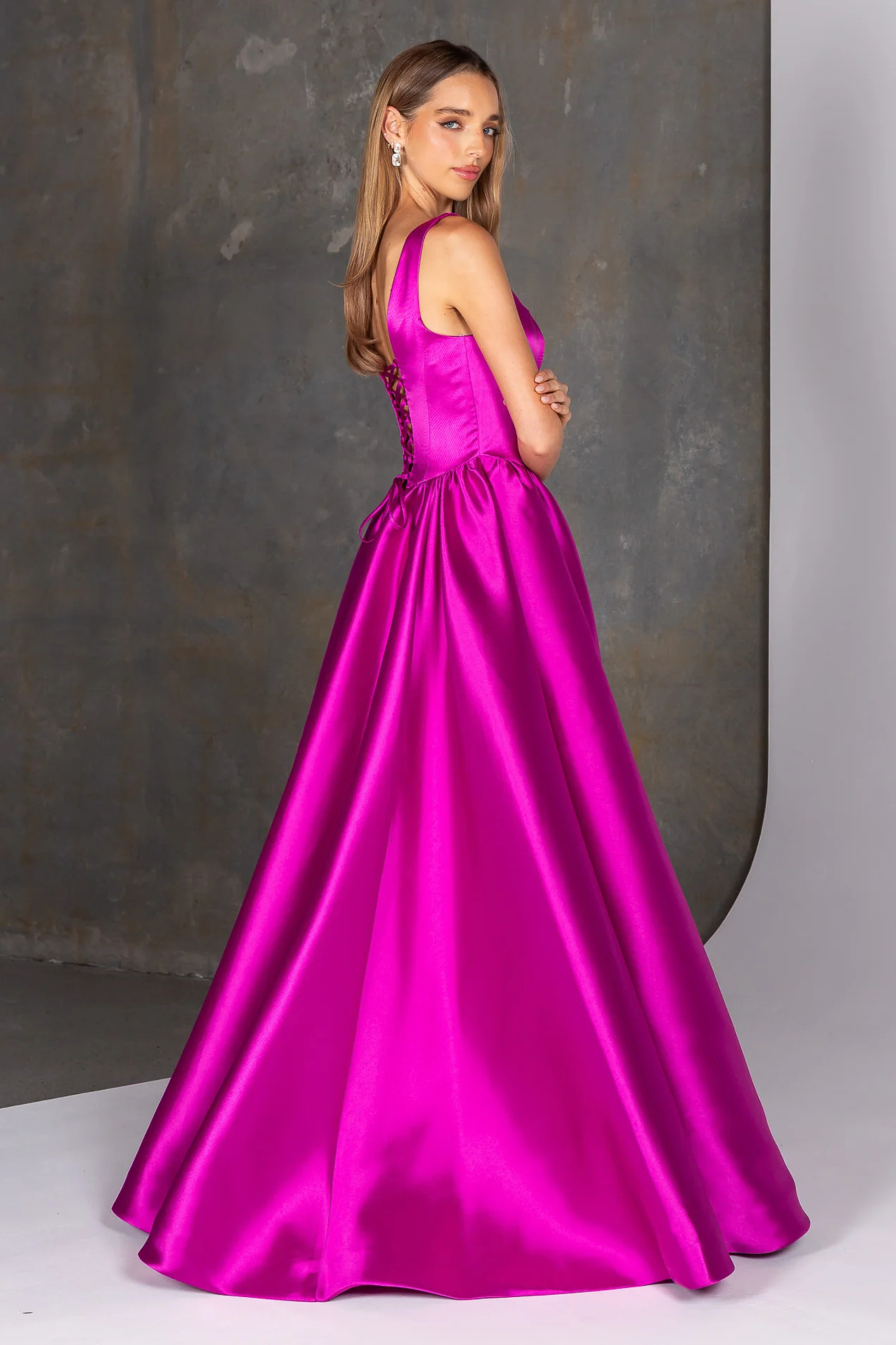 Woman wearing a magenta gown against a neutral background