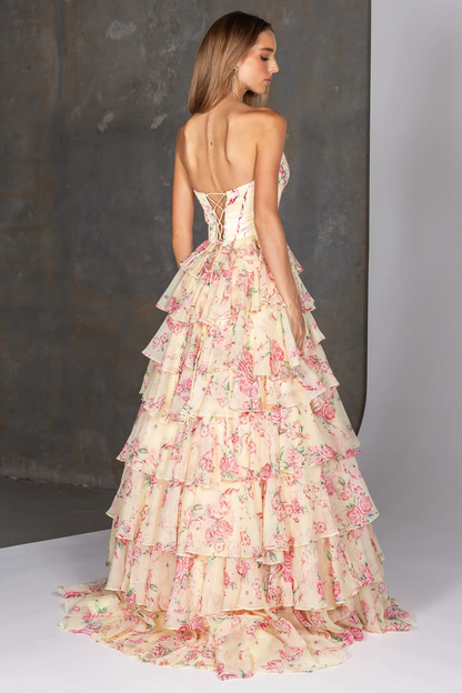 Woman wearing a yellow floral dress with a gray background showing the back of the dress design