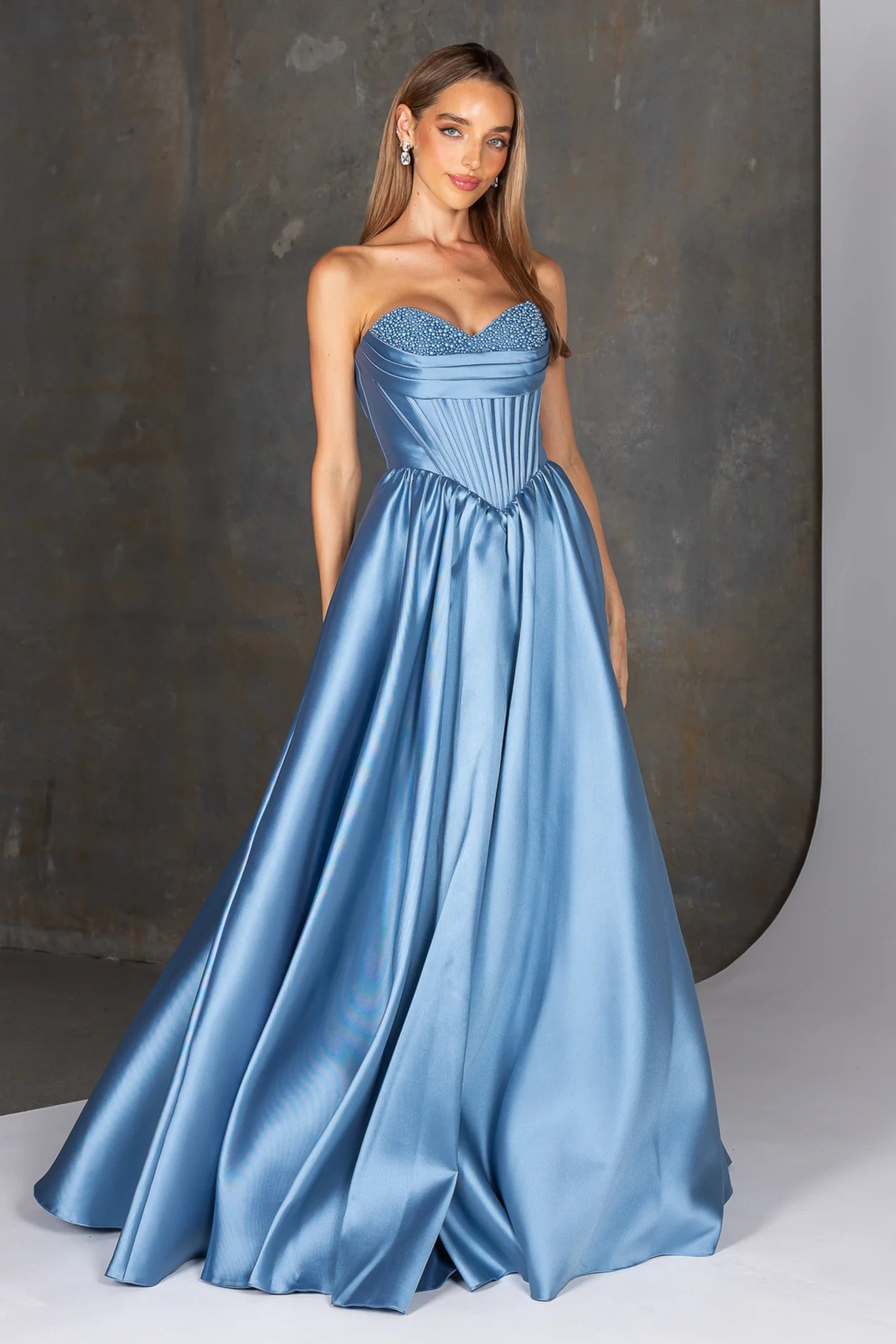 Woman wearing a blue strapless gown with a textured bodice against a neutral background