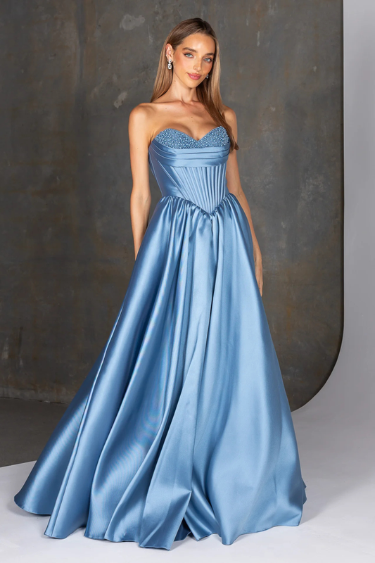 Woman wearing a blue strapless gown with a textured bodice against a neutral background
