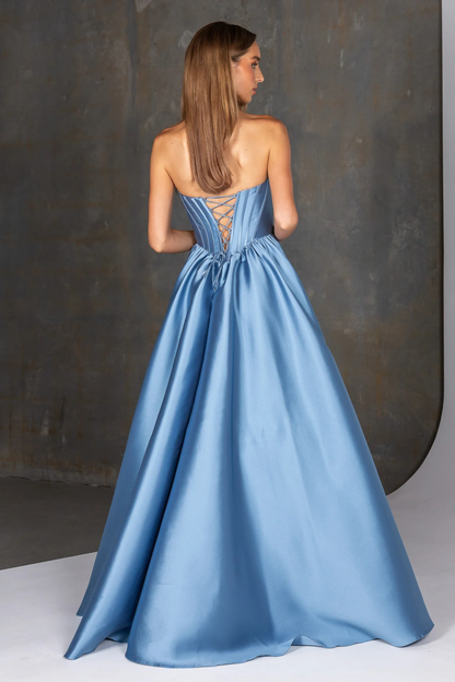 Woman wearing a blue evening gown with a lace-up back against a dark background