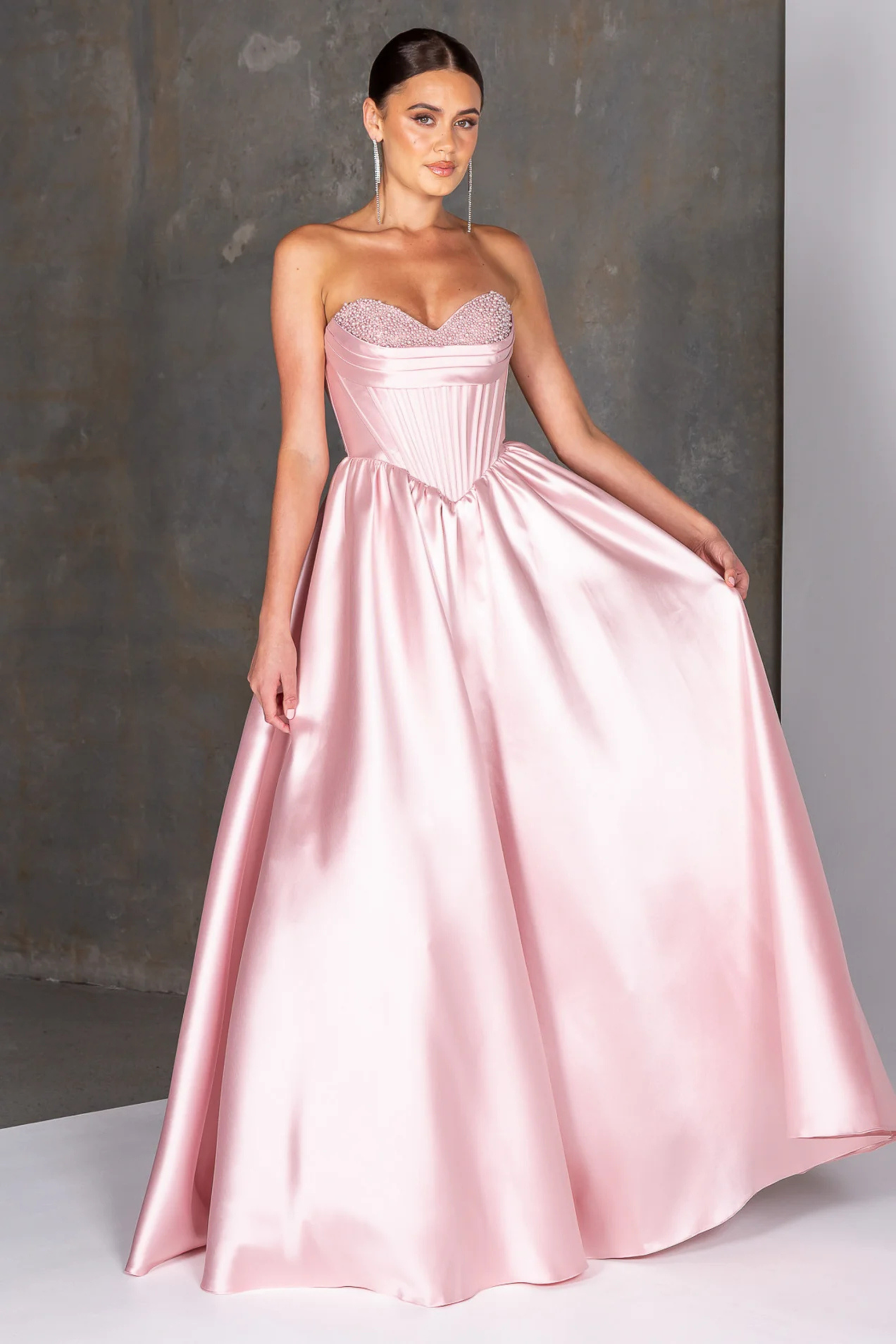 Pink strapless gown on a model against a neutral background