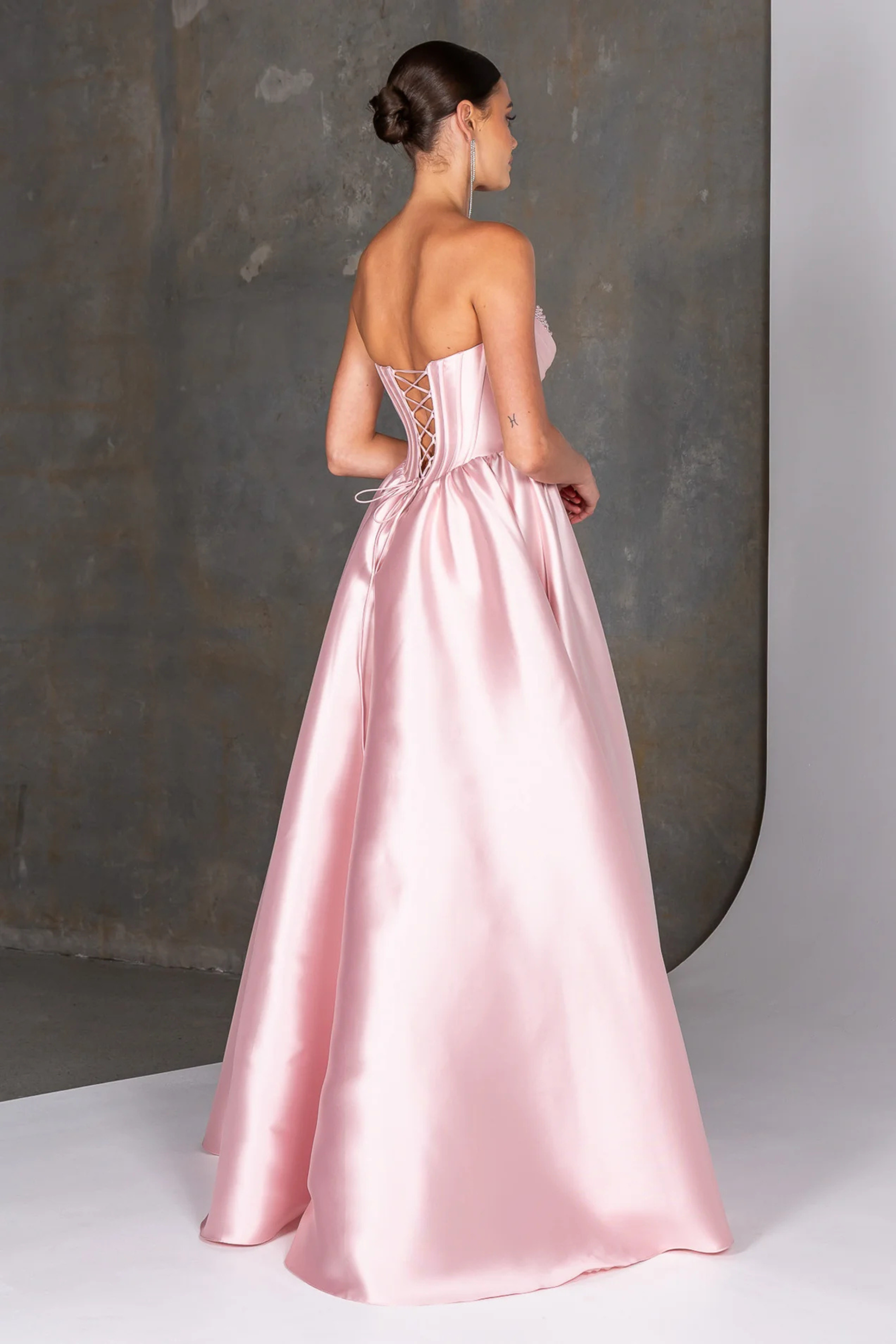 Pink satin gown with intricate back design on a neutral background