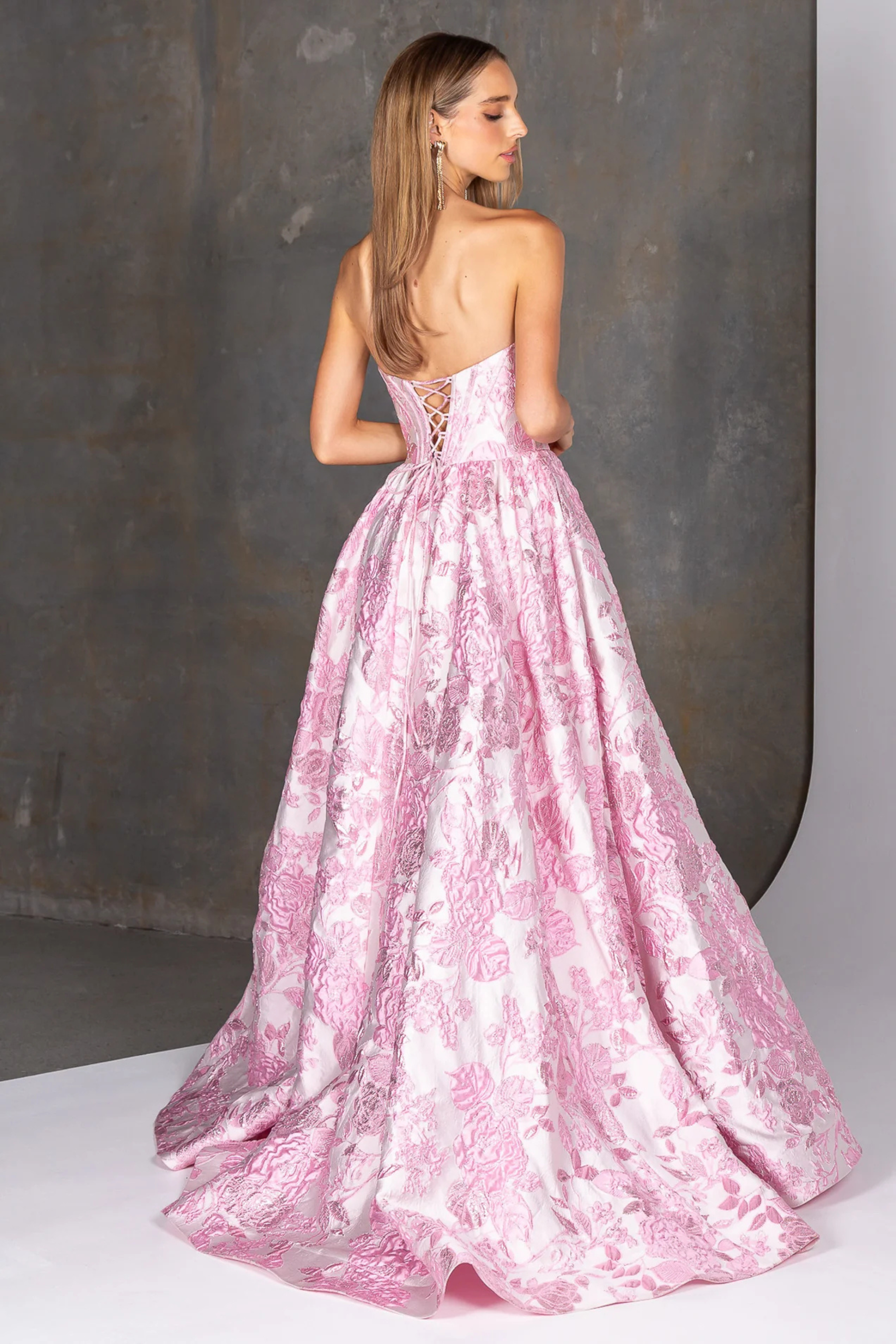 Woman wearing a pink floral evening gown against a neutral background
