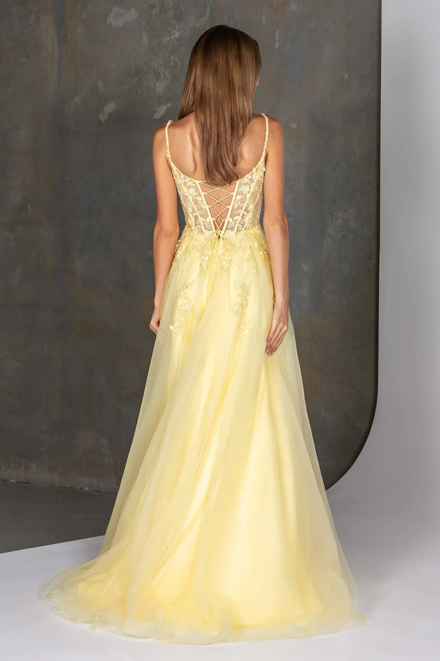 Woman wearing a yellow evening gown with a textured gray background