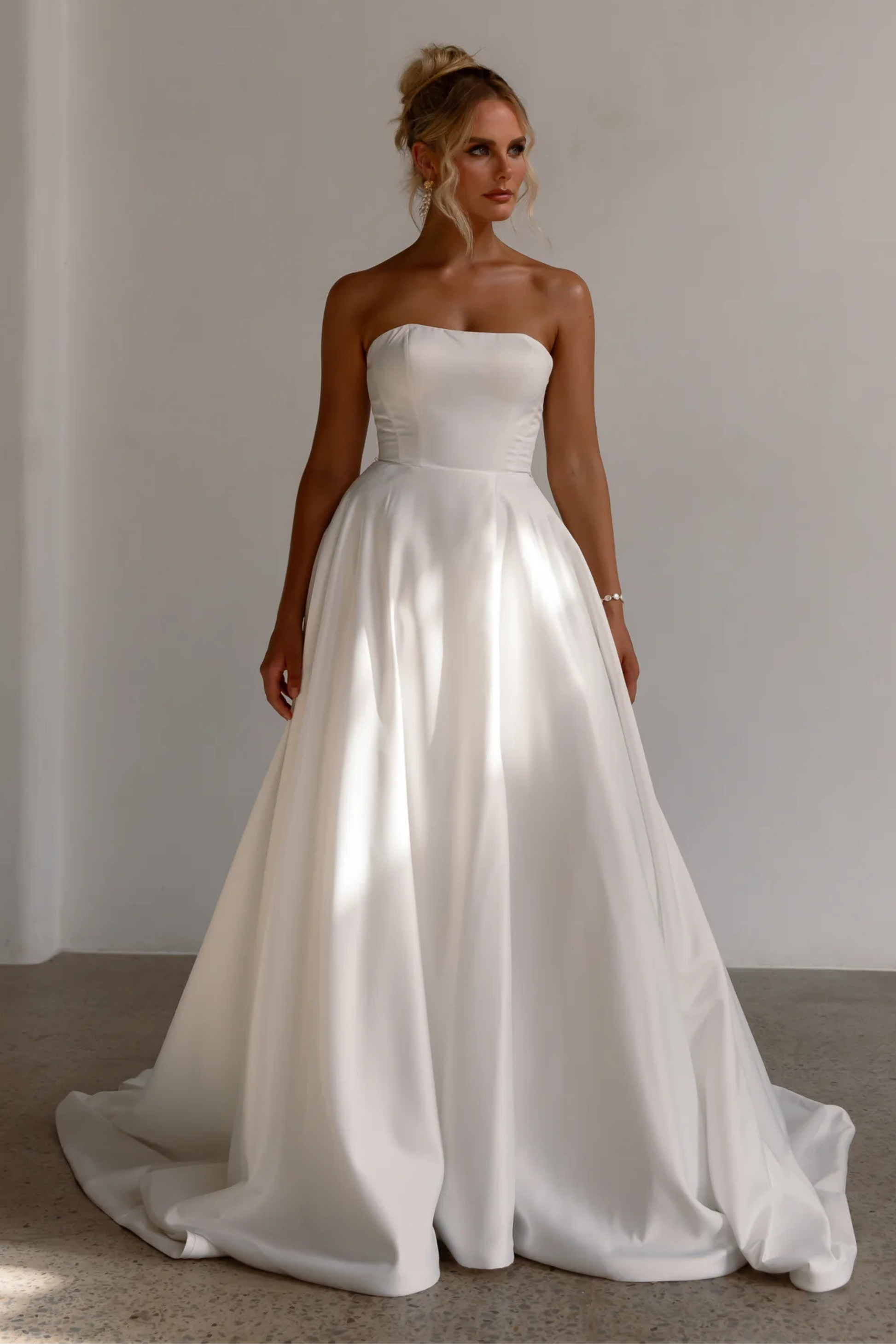 Tania Olsen Designs Anne wedding dress in vintage white featuring a square neckline, detachable bow straps, satin A-line skirt and chapel-length train.